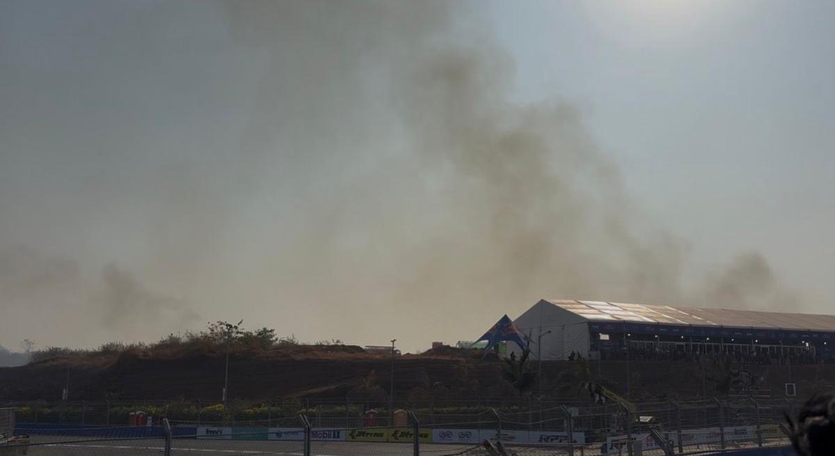 Smoke rising behind fan lounges following a dry-grass fire at the Indian Racing Festival in Goa.
