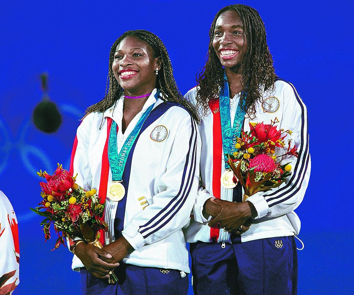 Venus Williams (R) and Serena Williams of the USA with their gold medal after winning the women’s doubles final at the Sydney 2000 Olympic Games.