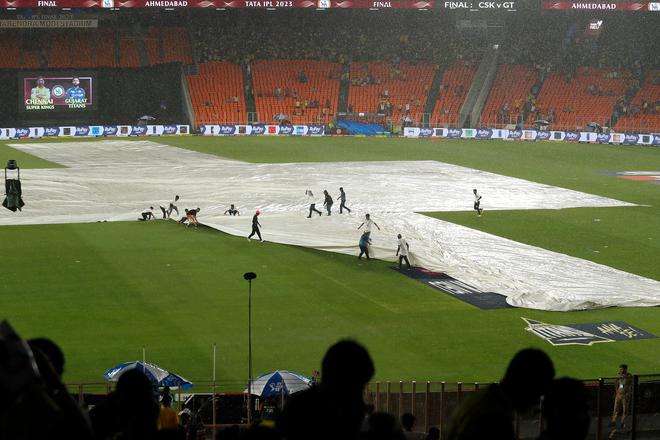 Ground staff place covers over the pitch as the downpour continues.