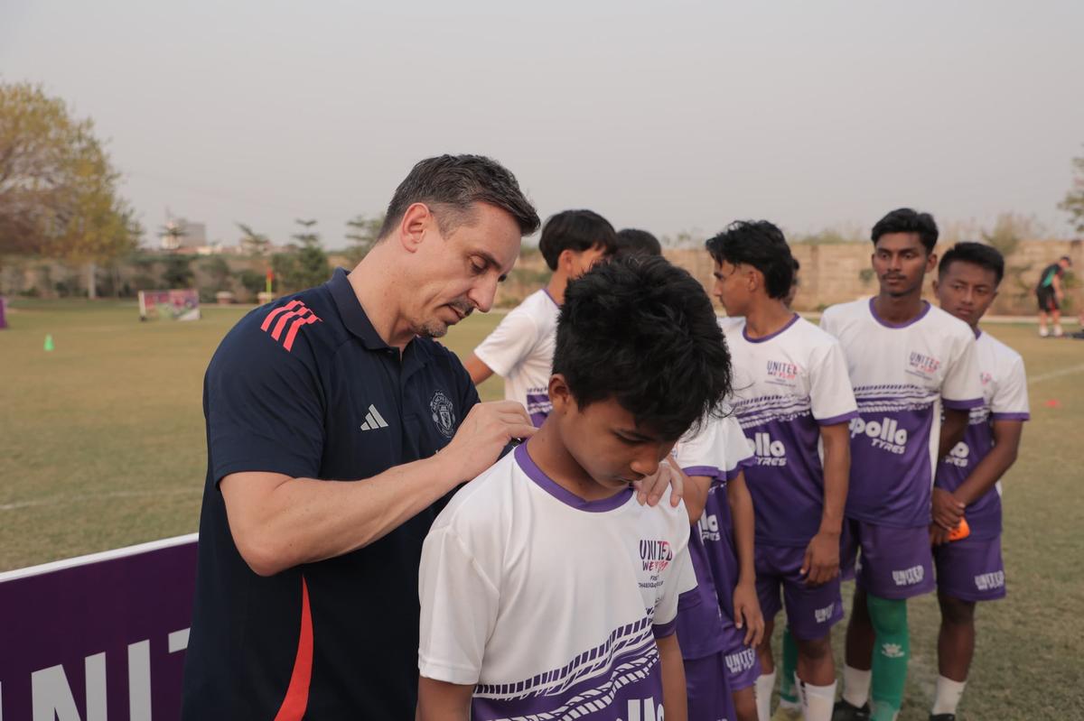 Gary Neville firma una camiseta para uno de los jóvenes futbolistas del programa United We Play.