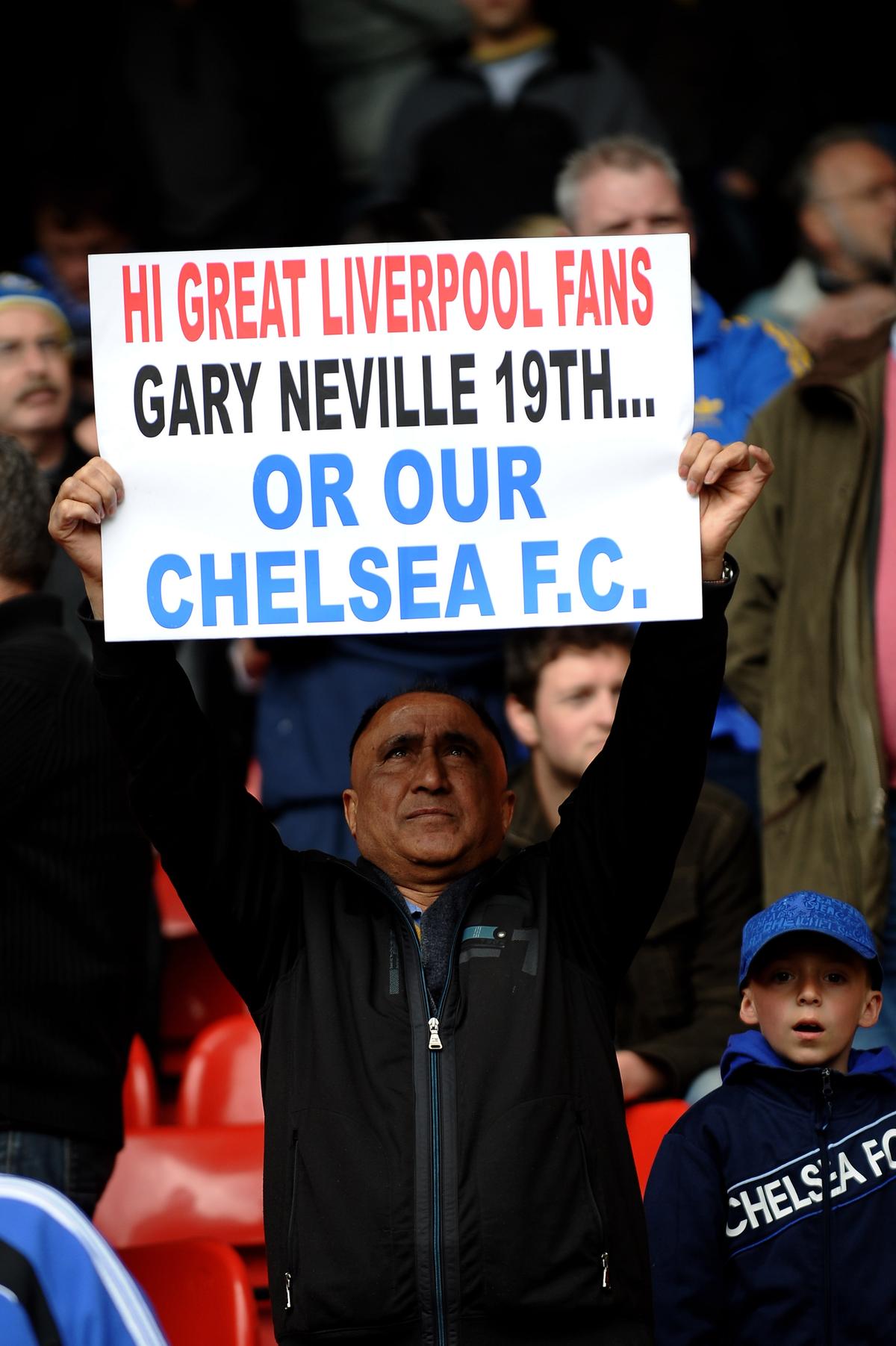 A Chelsea fan holds up a banner taunting Liverpool fans ahead of the match.