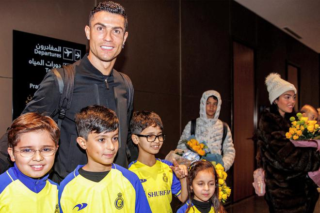 Cristiano Ronaldo posing for picture with Saudi children as his son Cristiano Ronaldo Jr (C) and partner Georgina Rodriguez (R) stand by.