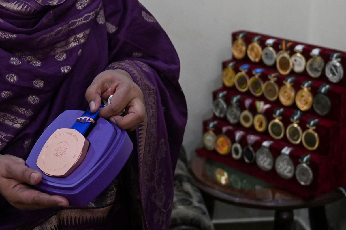 In this photograph taken on June 11, 2024 Samina Yaqoob, a major in Pakistan military’s nursing service shows a medal awarded to her daughter Kishmala Talat, the country’s first female to qualify for Olympic shooting, during an interview with AFP in Rawalpindi. 