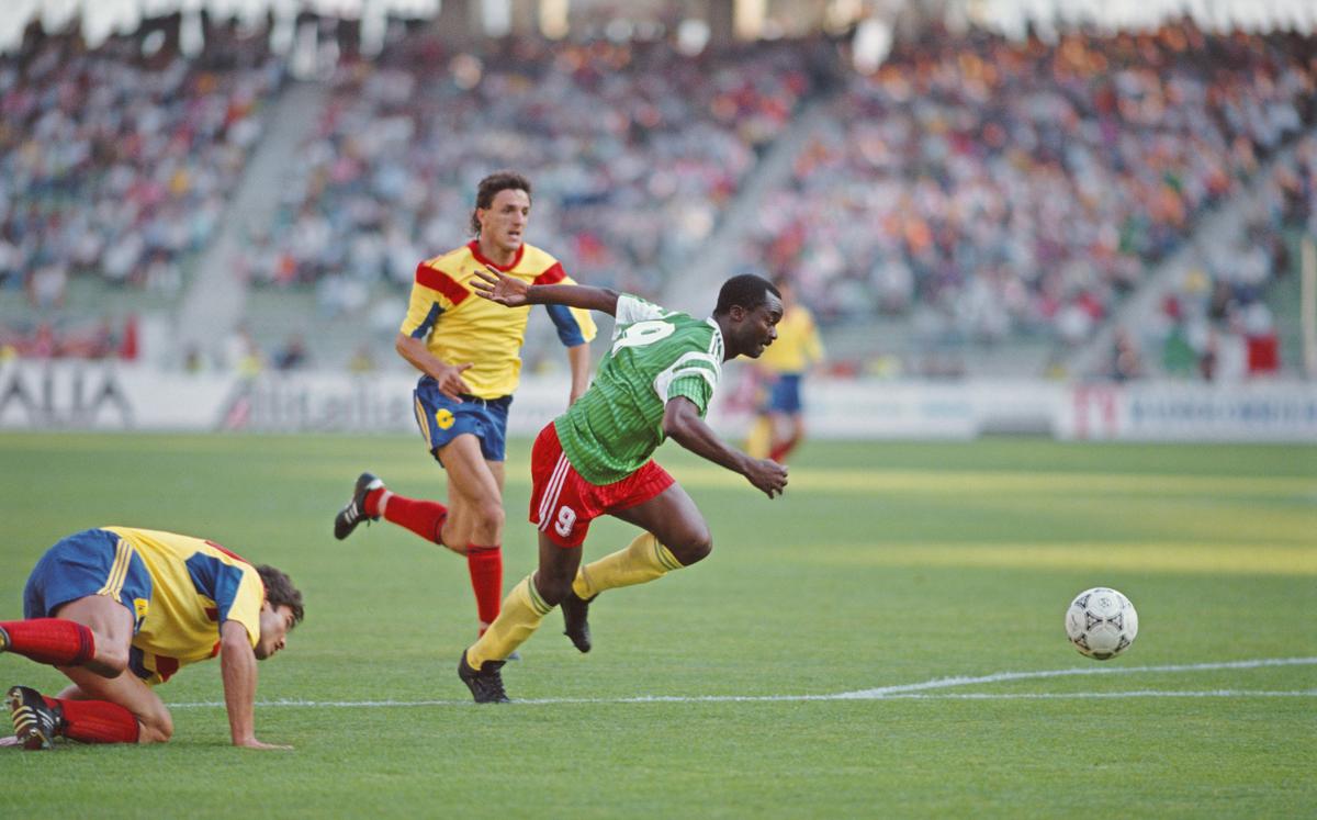 Le Camerounais Roger Milla dépasse les défenseurs roumains lors d'un match de groupe lors de la Coupe du Monde de la FIFA 1990.